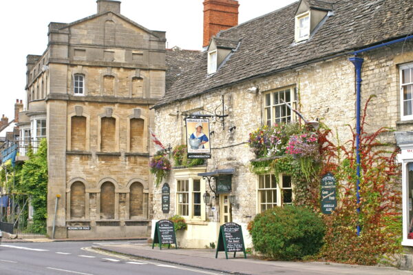 Exterior of a british pub with welcome signs and flowers on the pub wall